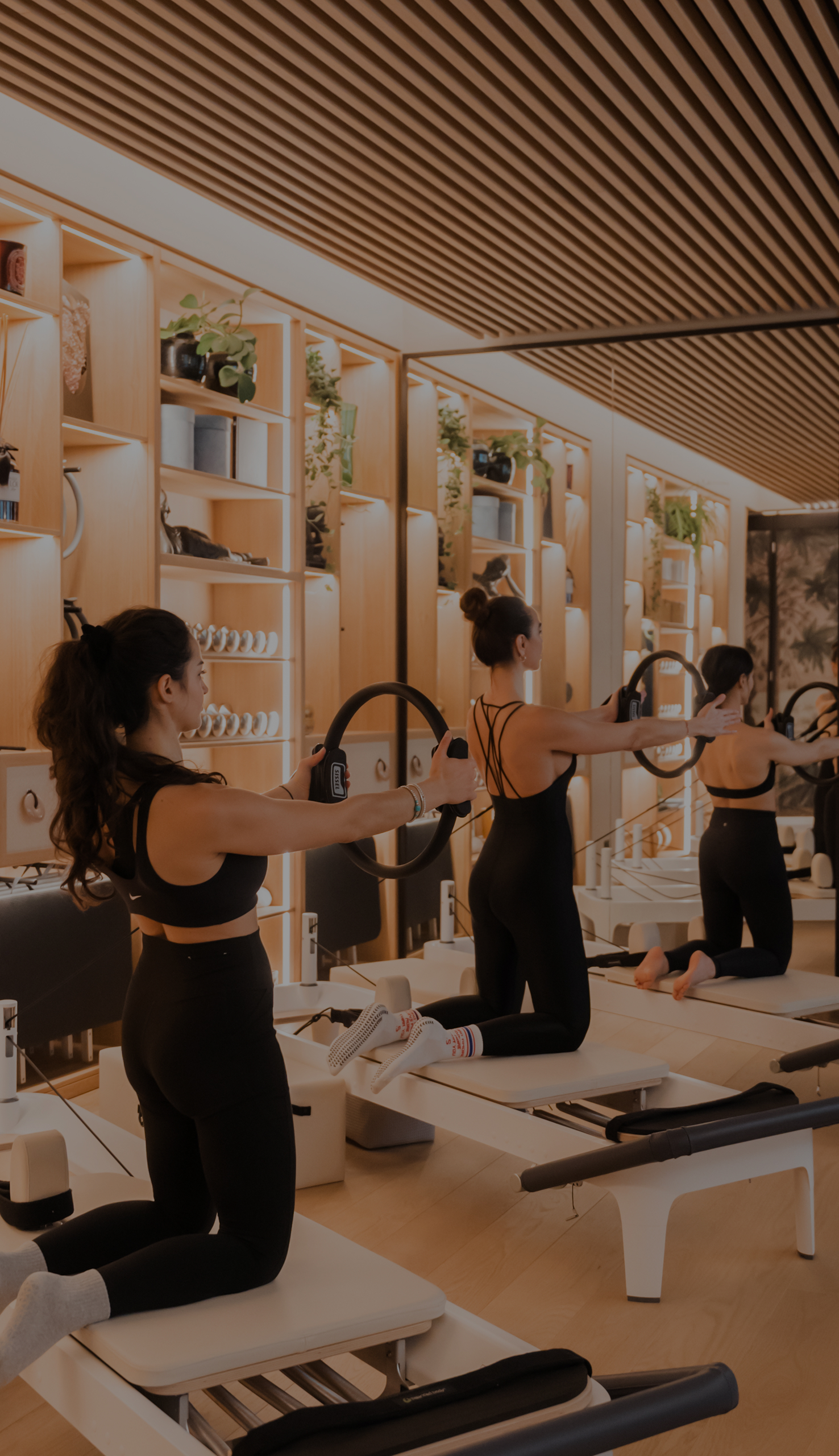 Foto che mostra tre persone che si allenano sui reformer nella sala Pilates di Studio Svetle Cavour