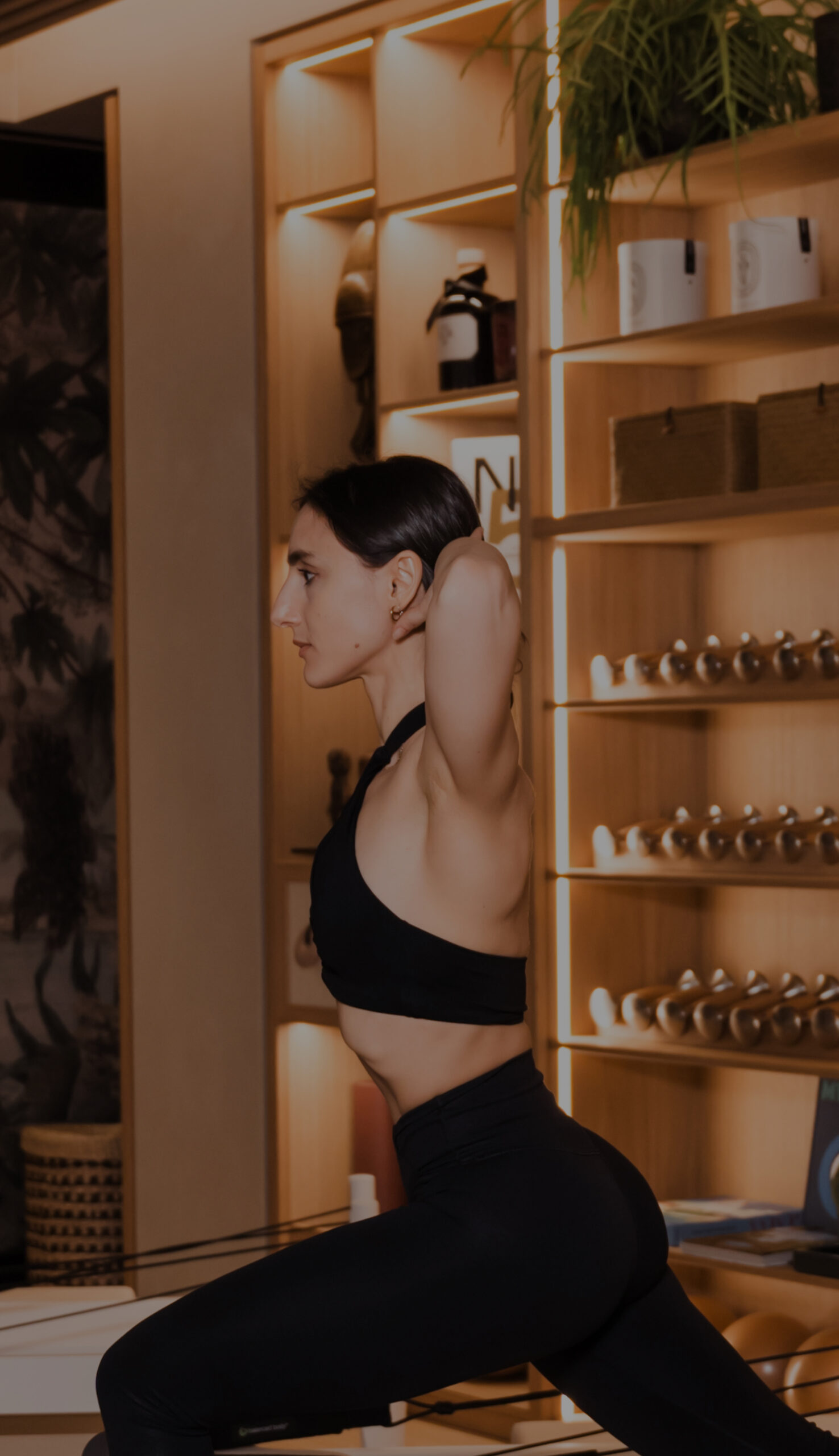 Foto di una donna vestita di nero che si allena su un reformer nella sala pilates di Studio Svetle Cavour